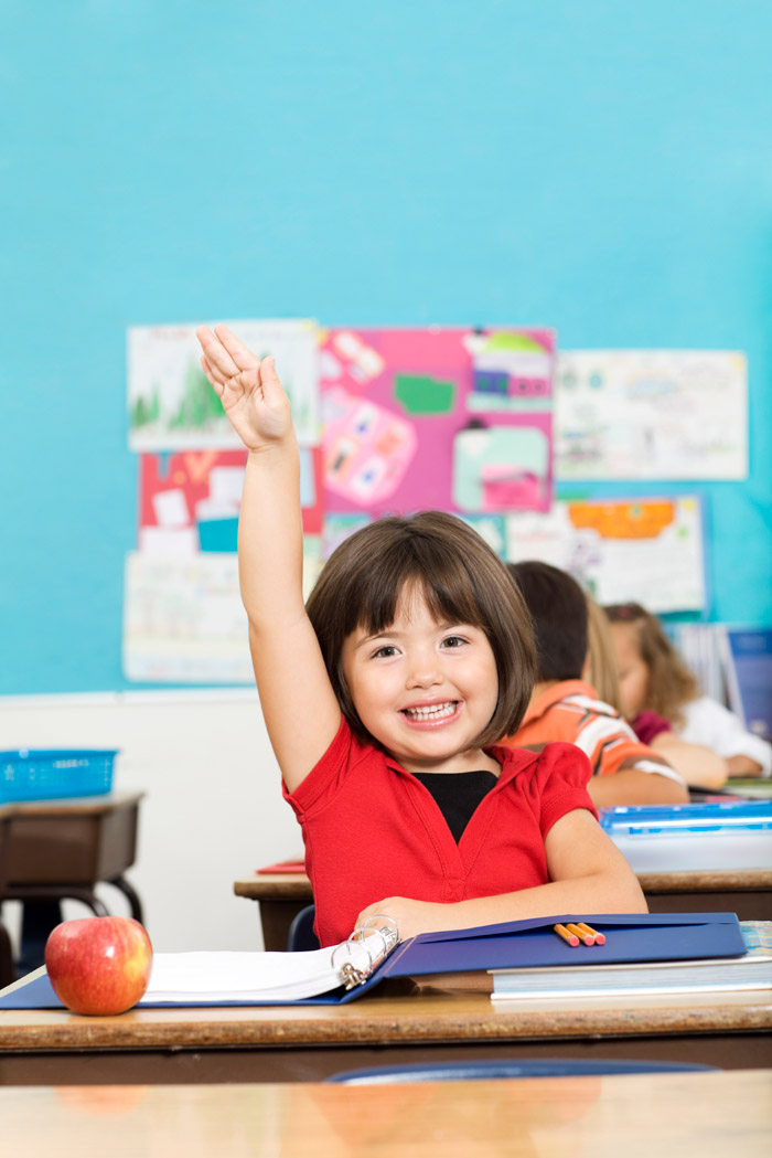 Smiling Abbotsford child in class holding his hand up