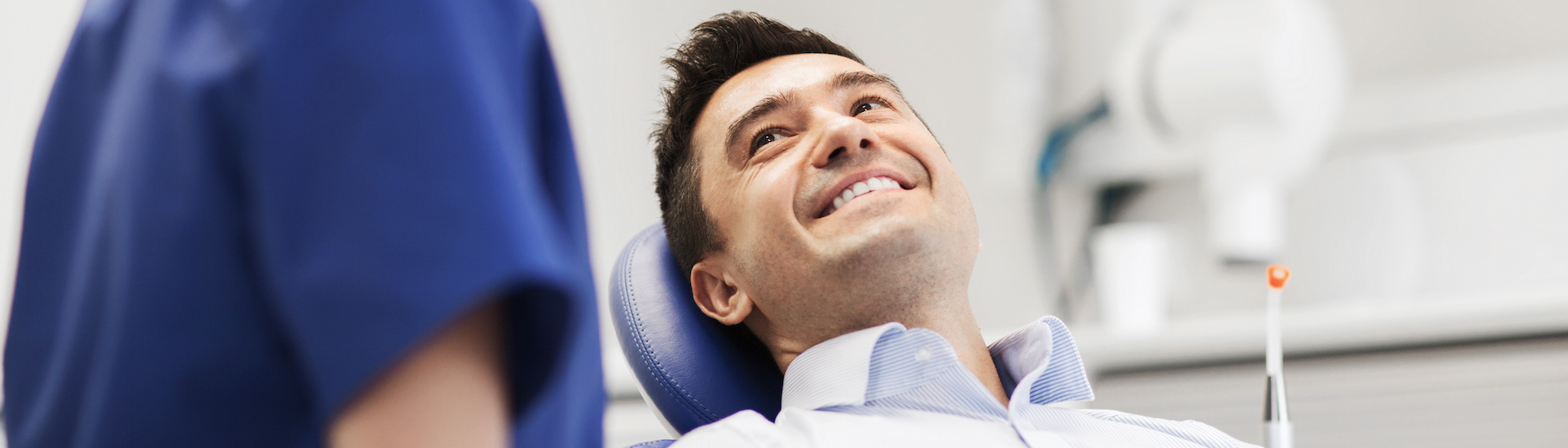 people, medicine, stomatology and health care concept - female dentist talking to happy male patient Dentist in Abbotsford